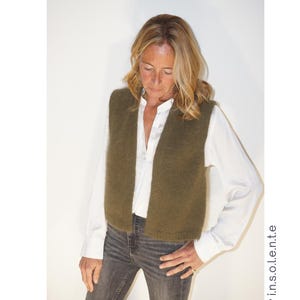 Peut inclure: Un gilet en tricot vert olive est porté sur une chemise blanche et un jean gris. Le mot "TOPAZE" est en haut à gauche. Le texte "Patron de tricot conçu en France" est en dessous. La difficulté est indiquée par trois diamants.