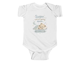 May include: A white short-sleeve bodysuit featuring a graphic of a sleeping teddy bear under a blue blanket with a crescent moon and stars. The text reads, Sugar, we're going down... for a nap, with small zzz symbols above the bear's head.