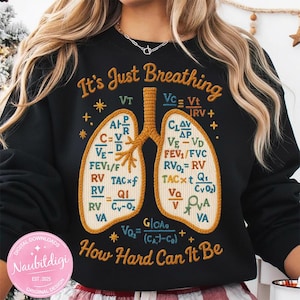 Könnte beinhalten: Schwarzes Sweatshirt mit gestickten Lungen und medizinischen Gleichungen. Der Text lautet "It's Just Breathing, How Hard Can It Be." Mit rundem rosa Aufkleber mit Text "Naubitdigi, Original Design, Est. 2025, Digital Downloads."