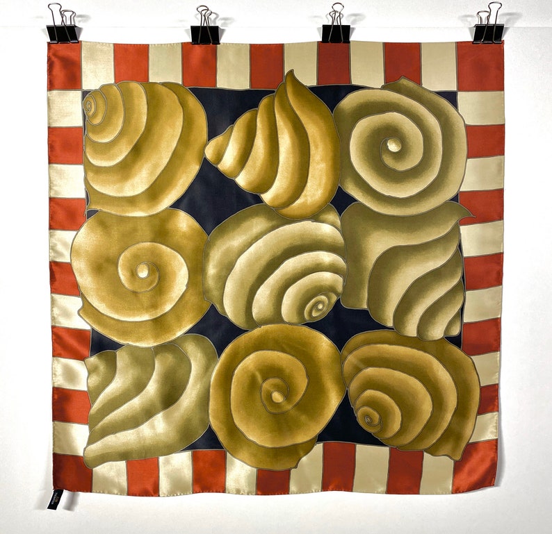 May include: A square silk scarf with a black background and a pattern of beige seashells. The scarf has a red and white striped border.