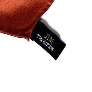 May include: A black fabric label with the text "JIM THOMPSON" in gold and white lettering.