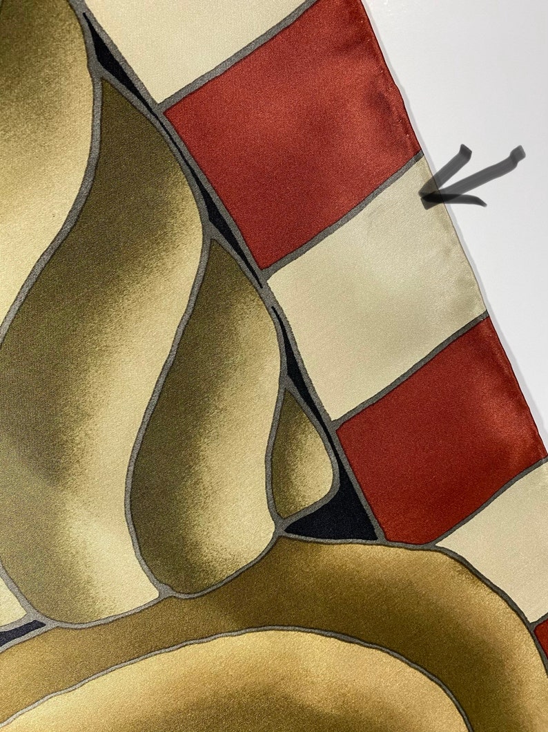 May include: A silk scarf with a geometric pattern in shades of brown, beige, red, and black. The scarf has a fringed edge.