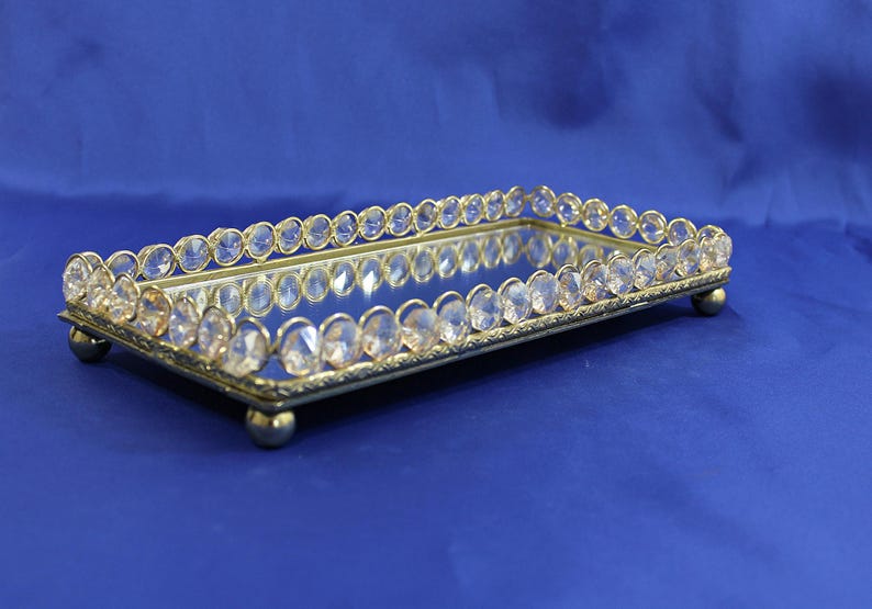 Contemporary style rectangular mirror tray with sparkly plastic crystals bordering the upper sides & ball feet on bottom.