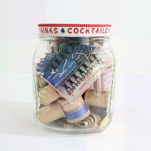 May include: A glass jar with a red lid and a white label that says "Sinks Cocktails". The jar is filled with various sewing supplies, including spools of thread, hooks, and eyes. The label on the jar also says "Brass-Rust? Ne" and "14 Each Hooks, Eyes & Loops".
