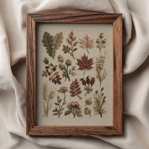 May include: A rectangular wooden frame containing a piece of fabric with detailed embroidery of various botanical elements, including oak leaves, maple leaves, acorns, wheat stalks, and wild berries in shades of green, brown, and muted red.