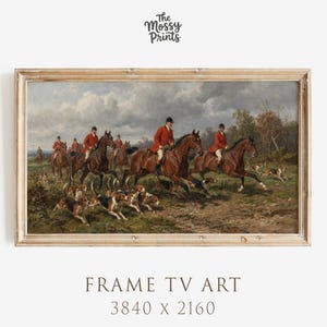 May include: A framed print of a vintage hunting scene. The artwork depicts riders in red coats on horseback, accompanied by hounds, pursuing prey across a field. The print is framed in a light-colored wooden frame. The text "FRAME TV ART" and dimensions are at the bottom.