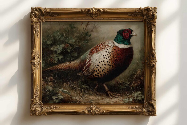 Op de afbeelding: Een schilderij van een fazant in een sierlijke gouden lijst. De vogel heeft een rode kop, groene nek en bruin-witte veren. Het kunstwerk is geplaatst tegen een achtergrond van bladeren.