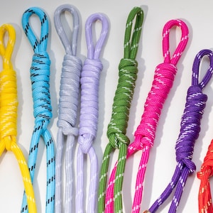 Peut inclure: Un ensemble de neuf cordons en nylon de différentes couleurs, notamment marron, jaune, bleu, gris clair, lavande, vert, rose, violet et rouge. Chaque cordon présente un motif tressé avec des coutures réfléchissantes blanches et une boucle.