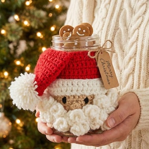 May include: A glass jar decorated as Santa Claus, filled with gingerbread cookies. The jar is adorned with a red and white crocheted Santa hat and beard. A tag with "Merry Christmas" hangs from the jar.