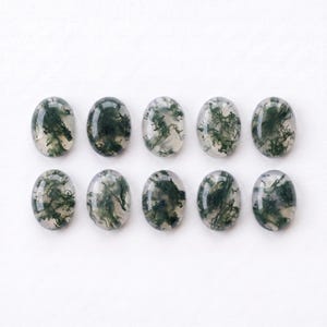 Pu&ograve; includere: Dieci cabochon di agata muschiata di forma ovale disposti in due file da cinque. Ogni gemma presenta una base traslucida bianco latte con distinte inclusioni dendritiche verde scuro che ricordano motivi a forma di muschio.