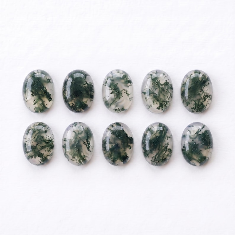 Pu&ograve; includere: Dieci cabochon di agata muschiata di forma ovale disposti in due file da cinque. Ogni gemma presenta una base traslucida bianco latte con distinte inclusioni dendritiche verde scuro che ricordano motivi a forma di muschio.