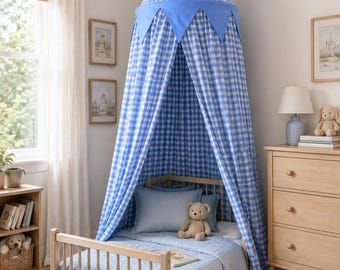 Può includere: Un baldacchino in tessuto a quadretti blu e bianco con una parte superiore a punta e dettagli a bandierina triangolare, sospeso sopra un letto per bambini in legno chiaro. Il letto presenta una trapunta trapuntata azzurra e un orsacchiotto.
