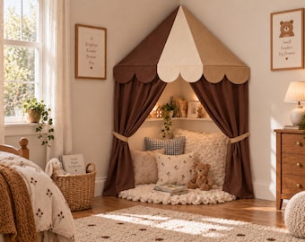 Può includere: Una tenda da gioco angolare con un baldacchino smerlato marrone e crema e tende marroni abbinate raccolte. L'interno include un morbido tappeto circolare bianco, vari cuscini, un orsacchiotto e una piccola mensola angolare.