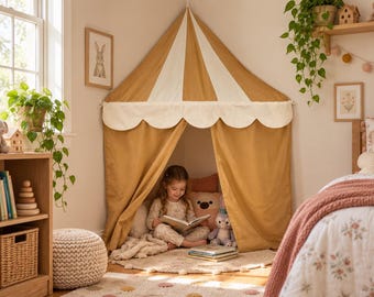 Può includere: Una tenda da gioco in tessuto color giallo senape e crema con tetto a punta e mantovana smerlata. La tenda è posizionata in un angolo, creando un angolo accogliente con tende aperte che rivelano uno spazio per leggere e giocare all'interno.