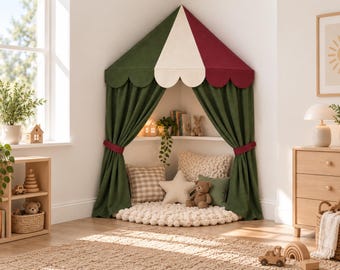 Può includere: Una tenda da gioco angolare con un baldacchino smerlato in verde scuro, crema e bordeaux. La tenda presenta tende verde scuro legate con fasce bordeaux, rivelando un interno accogliente con un tappeto bianco, un cuscino a stella e peluche.