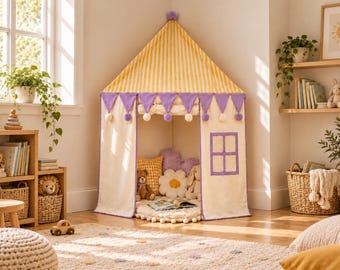 Può includere: Una tenda da gioco angolare con tetto conico a righe gialle e bianche e un pompon viola sulla punta. Le pareti in tessuto color crema presentano bandierine triangolari viola con pompon bianchi, una finestra quadrata e un ingresso aperto.