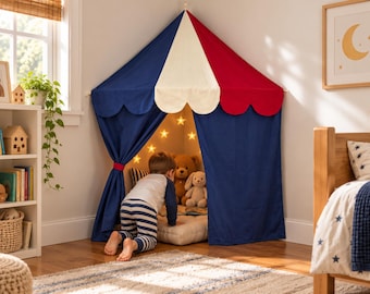 Può includere: Una tenda da gioco angolare con tetto triangolare a pannelli alternati in tessuto blu navy, crema e rosso. La tenda presenta bordi smerlati, tende con lacci e luci a forma di stella all'interno che illuminano peluche.