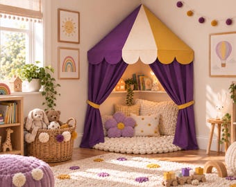 Può includere: Una tenda da gioco angolare caratterizzata da un baldacchino a righe viola e gialle con bordi smerlati e tende viola abbinate legate con fasce gialle. L'interno include un cuscino da pavimento bianco testurizzato e vari cuscini decorativi.