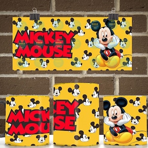Peut inclure: Un mug en c&eacute;ramique jaune avec un motif r&eacute;p&eacute;titif de t&ecirc;tes de Mickey Mouse et le texte MICKEY MOUSE en lettres rouges grasses. Le design comprend une illustration plus grande de Mickey Mouse posant son menton sur ses mains sur fond jaune.