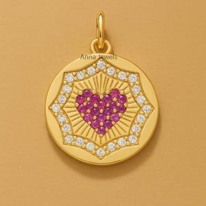 May include: A gold pendant featuring a heart made of pink gemstones, encircled by a starburst design and white gemstones. The pendant has the text "Anna Jewels". A stylish piece of jewellery.