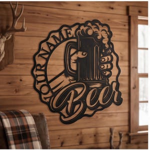 Könnte beinhalten: Ein schwarzes Metall-Wandschild mit einer Hand, die einen schaumigen Bierkrug hält. Das Design enthält den Text "YOUR NAME" entlang der linken Seite und das Wort "Beer" in großer Schreibschrift unten, was ein rundes dekoratives Wandobjekt ergibt.