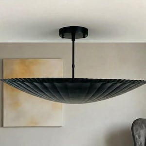 Puede incluir: Una lámpara de techo negra y moderna con una gran pantalla festoneada. La pantalla tiene forma de cuenco y cuelga de una varilla negra y un soporte de techo. La lámpara es una adición elegante a cualquier habitación.