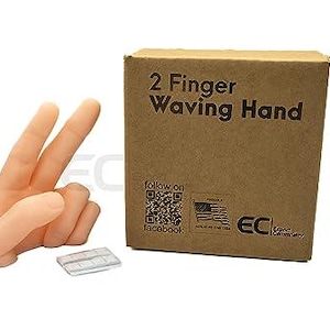May include: A prosthetic hand with two fingers extended in a peace sign, next to a cardboard box. The box is labeled "2 Finger Waving Hand" and includes a QR code and the American flag.