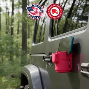 May include: A red phone holder attached to a green vehicle door. The phone holder has a teal-colored phone in it. The image includes a "Made in USA" sticker and a "Fast Shipping" sticker.