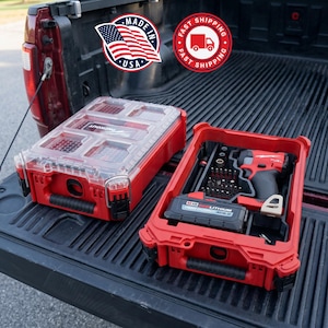 May include: Two red PACKOUT toolboxes with clear lids sit in the bed of a truck. One toolbox is closed, and the other is open, revealing a drill, bits, and a battery. The image includes a "Made in USA" sticker and a "Fast Shipping" logo.
