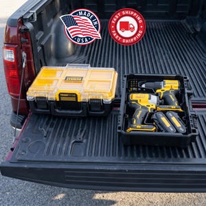 May include: Yellow and black ToughSystem toolboxes and power tools in a truck bed. The toolbox has a clear lid and black latches. The power tools include a drill, impact driver, and batteries. The image includes a "Made in USA" sticker.