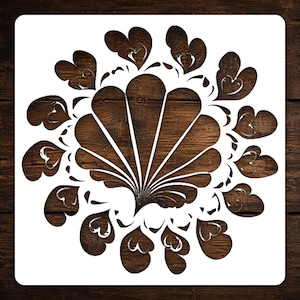 May include: White stencil featuring a symmetrical design of stylized hearts and fan-like shapes. The stencil is set against a dark brown wood grain background, creating a contrast. Ideal for crafting and decorative projects.