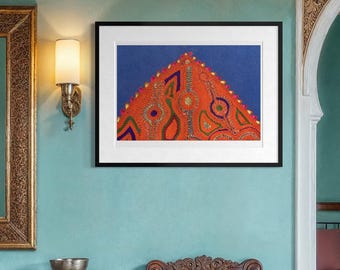 May include: A framed rectangular art print featuring a triangular orange motif with colorful abstract patterns on a blue background, displayed on a teal wall between two wall sconces, above a wooden console table and a carved wooden chair.