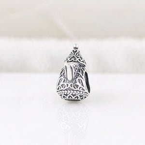 Puede incluir: Un charm de plata con un diseño de filigrana ornamentado. El charm tiene una parte superior cónica y una base redondeada, con intrincados patrones por todas partes. El charm probablemente está hecho de plata de ley y está diseñado para ser añadido a una pulsera o collar.