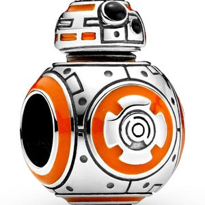 Pode incluir: Um berloque BB-8 prateado e laranja. O berloque apresenta um design detalhado com detalhes em laranja e preto. A parte superior do berloque tem uma forma arredondada com círculos pretos. O corpo é uma esfera com detalhes em laranja e prata.