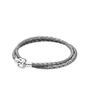 May include: A gray braided leather bracelet with a silver clasp. The bracelet is double-stranded and features a woven design. The clasp has the letters "PAN" engraved on it. The bracelet is displayed on a white background.