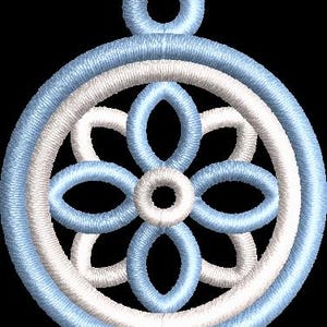 以下が含まれることがあります： 水色と白の刺繍オーナメント。円形のデザインで、中央に花のような模様があります。吊り下げ用のループが付いています。デザインは黒い背景にあります。