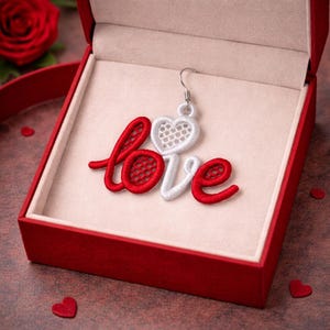 May include: A red gift box contains a single earring spelling "love" in red and white embroidery. The "love" design features a white heart and a red, open-weave design. A red rose and heart-shaped confetti are visible.