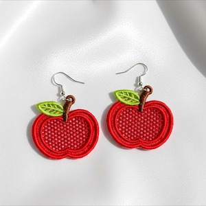 Peut inclure: Une paire de boucles d'oreilles en forme de pomme rouge avec des feuilles vertes et des tiges marron. Les boucles d'oreilles sont brodées d'un motif en forme de filet à l'intérieur de la pomme et ont des crochets argentés.