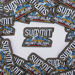Peut inclure: Un écusson brodé rectangulaire affichant le mot SUMMIT en lettres blanches au-dessus d'un graphique de montagne bleue. Sous la montagne, le texte indique 4806 METERS MONT-BLANC avec une fine bande horizontale aux couleurs verte, blanche et rouge.