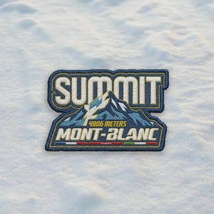 May include: Embroidered patch with the word "SUMMIT" in white letters on a navy blue background. Below, a mountain graphic with the text "4806 METERS MONT-BLANC" is displayed. The patch has a yellow border and is set against a snowy backdrop.