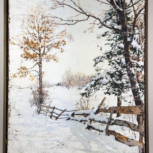 May include: A framed winter landscape painting. The artwork depicts a snow-covered path winding through a forest, with a wooden fence and trees. The color palette includes white, brown, and touches of gold.