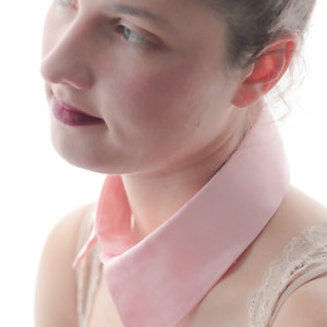 May include: A woman with a pink collar and a lace-trimmed top. The collar is a simple, wide, and flat design.