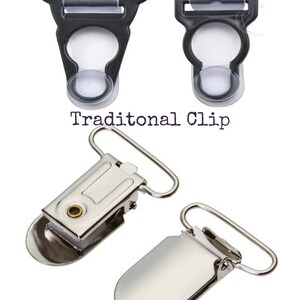 K&ouml;nnte beinhalten: Zwei Arten von Hosentr&auml;ger-Clips. Der erste ist ein traditioneller schwarzer Plastikclip mit einem transparenten Plastikeinsatz. Der zweite ist ein silberner Metall-Krokodilclip.