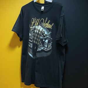 May include: Black t-shirt featuring a graphic of a man in a patterned jacket, leaning against a classic car. The words "Old School" are written in a stylized, yellow font above the image. The shirt has short sleeves and a crew neck.
