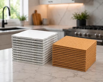 May include: Two stacks of square coasters. One stack is white, the other is a natural cork color. The coasters are stacked neatly on a light-colored countertop. The background shows a kitchen with a sink, stove, and window.