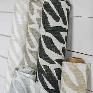 May include: Four rolls of fabric with a white background and a black and white leaf pattern. The fabric rolls are arranged vertically and are hanging on a white wall.