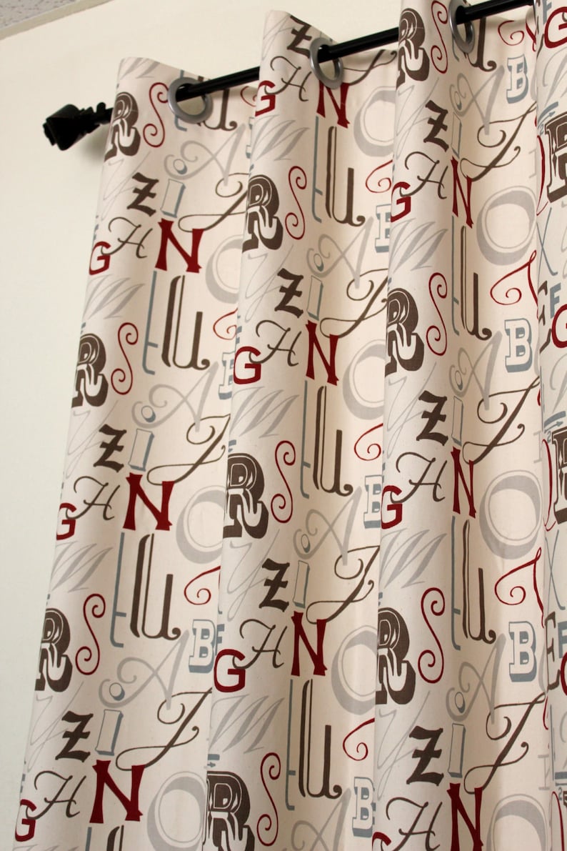 May include: Curtains with a cream background and a pattern of letters in red, brown, and grey. The letters are stylised and include the letters A, B, G, N, R, S, U, and Z.
