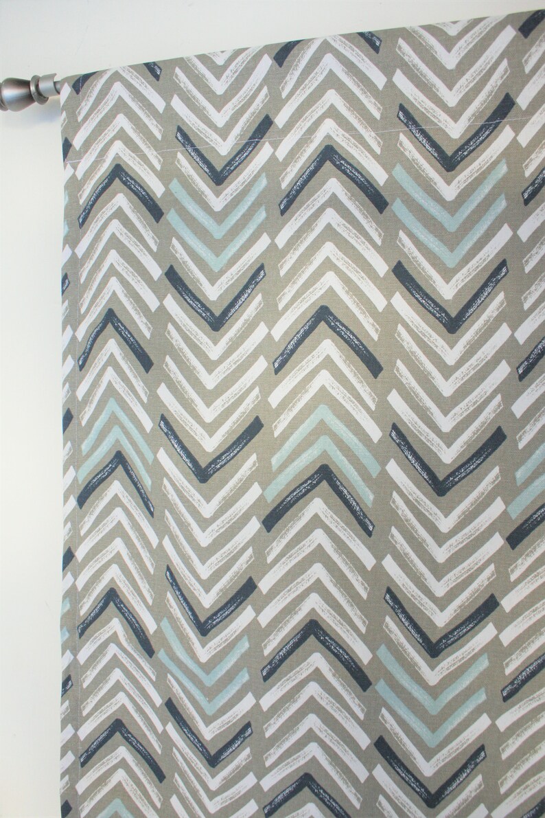 Puede incluir: Un panel de cortina con un patr&oacute;n de chevron en tonos de gris, azul y blanco. La tela tiene una apariencia texturizada, similar al lino.