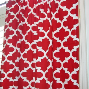 May include: Red curtains with a white geometric pattern. The curtains are hung on a window.