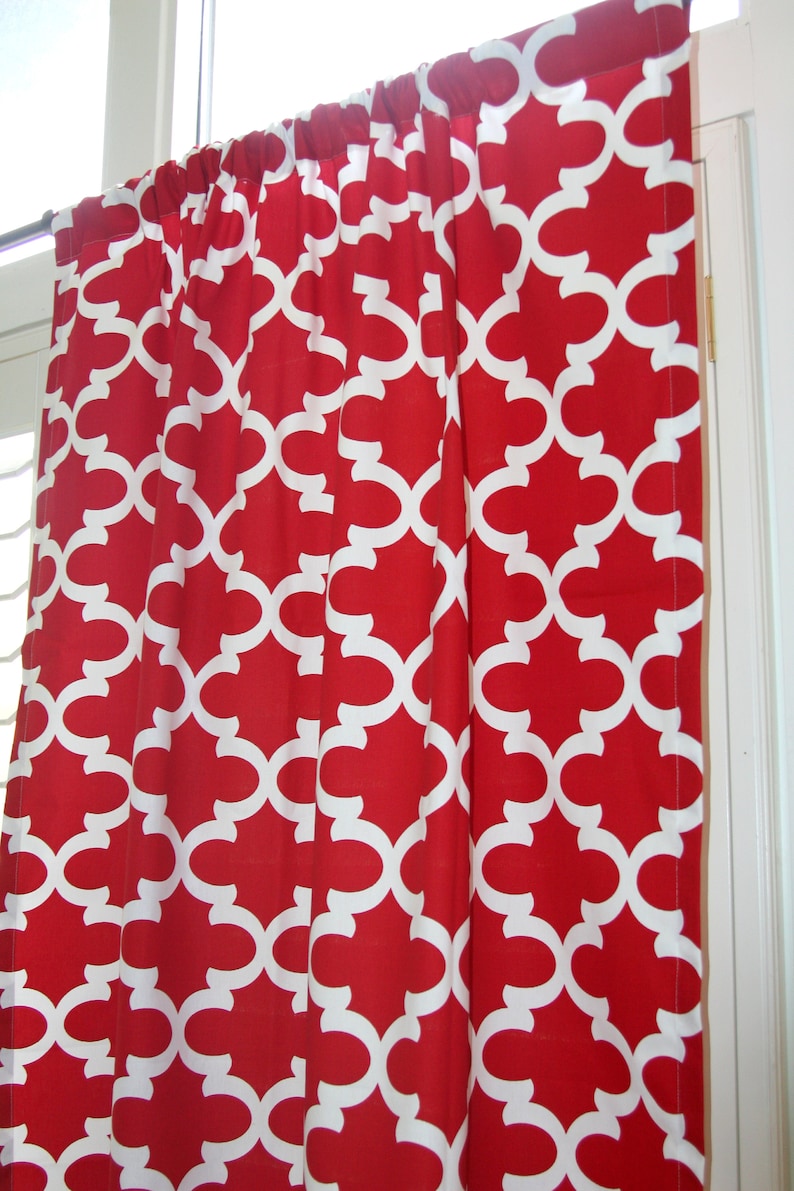 May include: Red curtains with a white geometric pattern. The curtains are hung on a window.